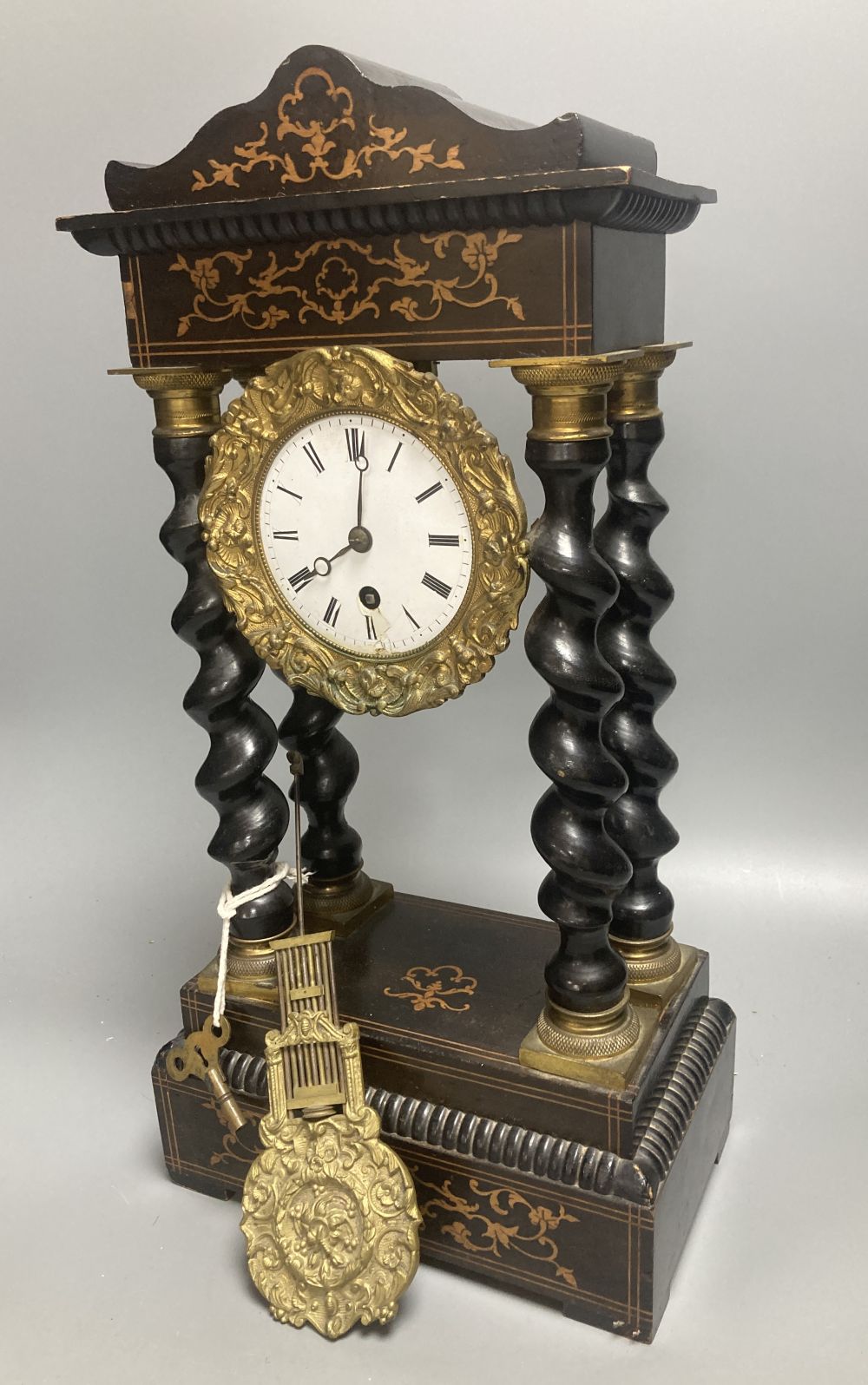 A 19th century French portico ebonised mantel clock, enamelled dial and timepiece movement, gridiron pendulum, 44cm high
